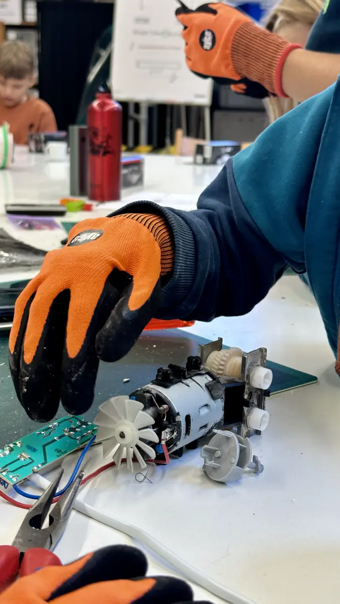 Mit Schutzhandschuhen wird ein alter Motor zerlegt