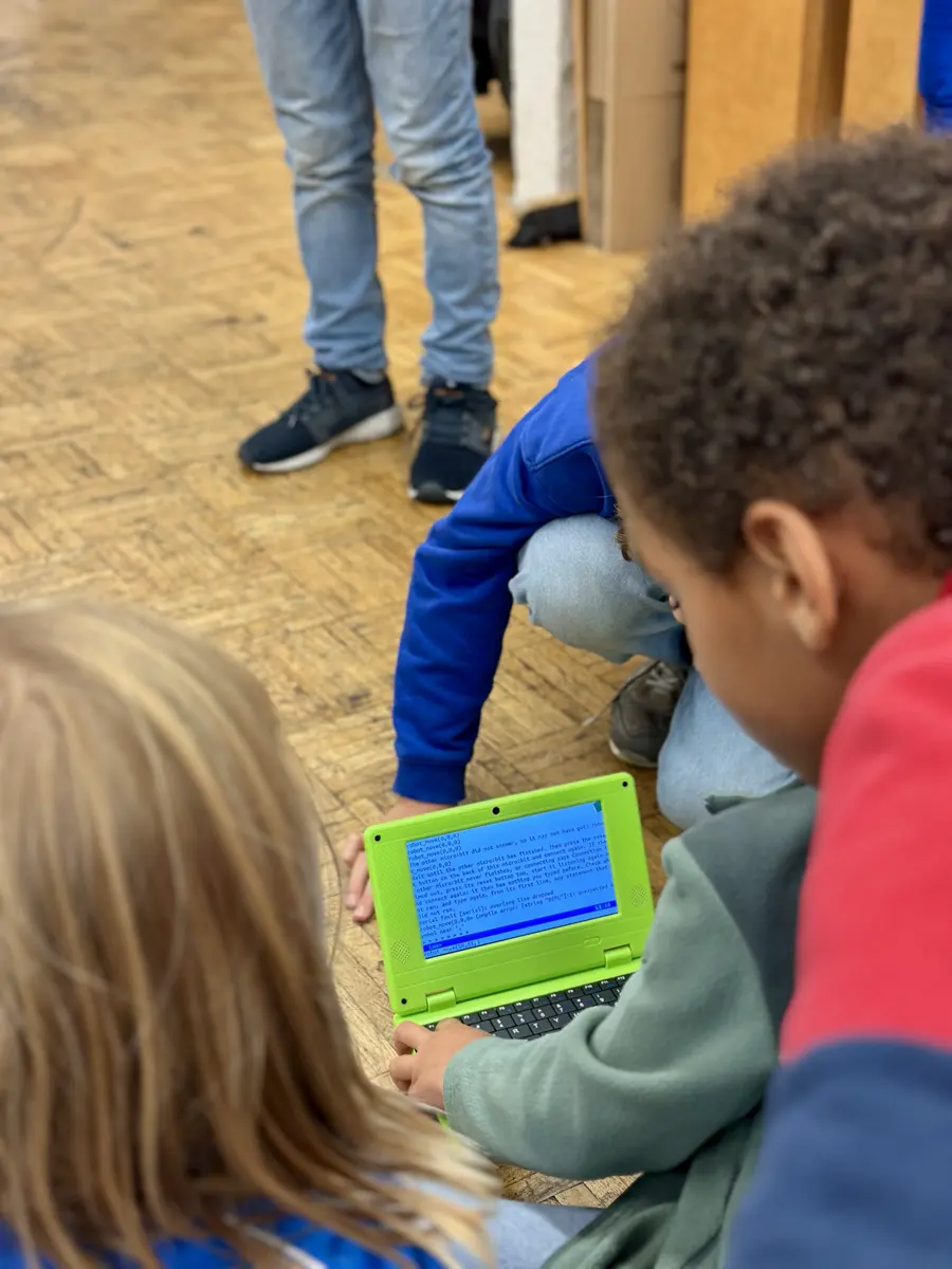 Kinder sitzen mit Laptops am Boden und programmieren